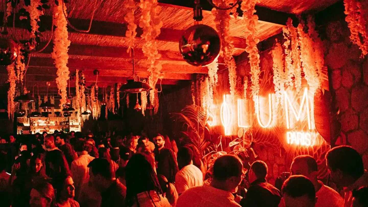 Inside Solum nightclub in Paris, with neon sign and lively crowd