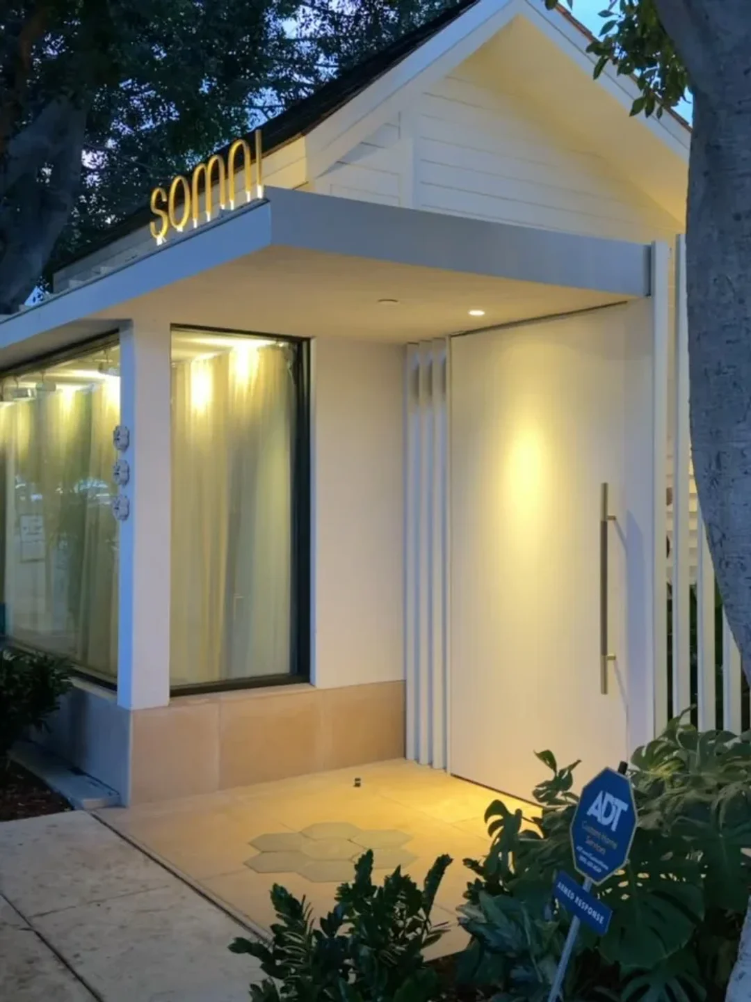 Modern exterior of Somni restaurant in the city at dusk with illuminated signage and clean architectural lines.