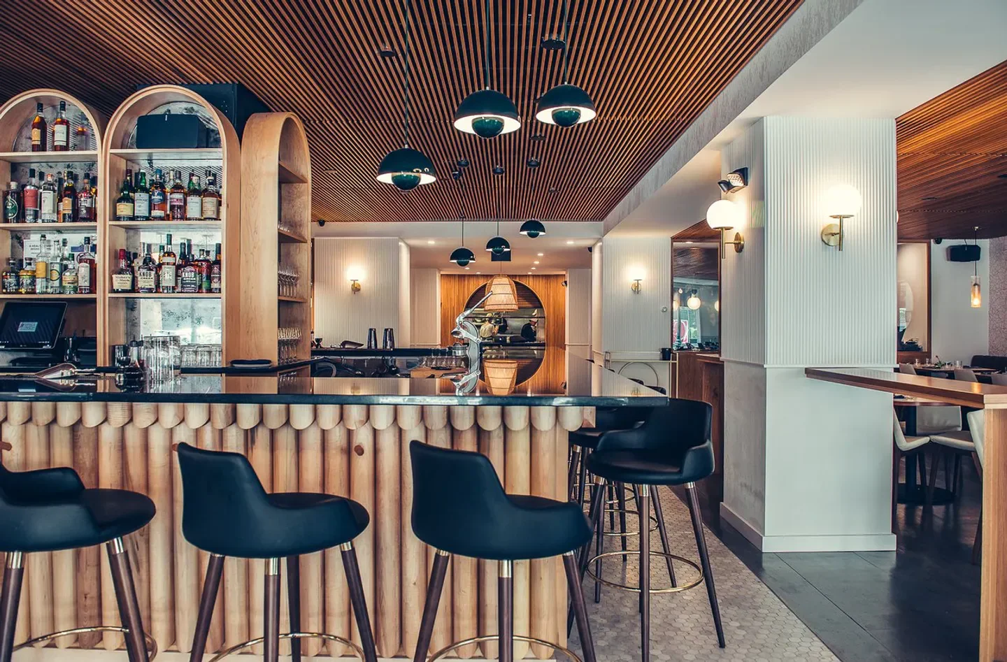 Stylish bar at Spice Finch restaurant in Philadelphia with wooden decor and black chairs.