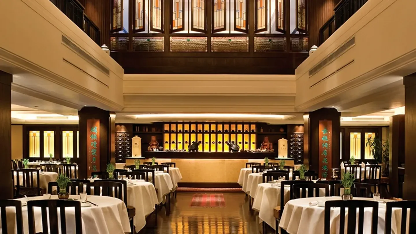Elegant dining room interior at Spring Moon restaurant in Hong Kong, with tables set.