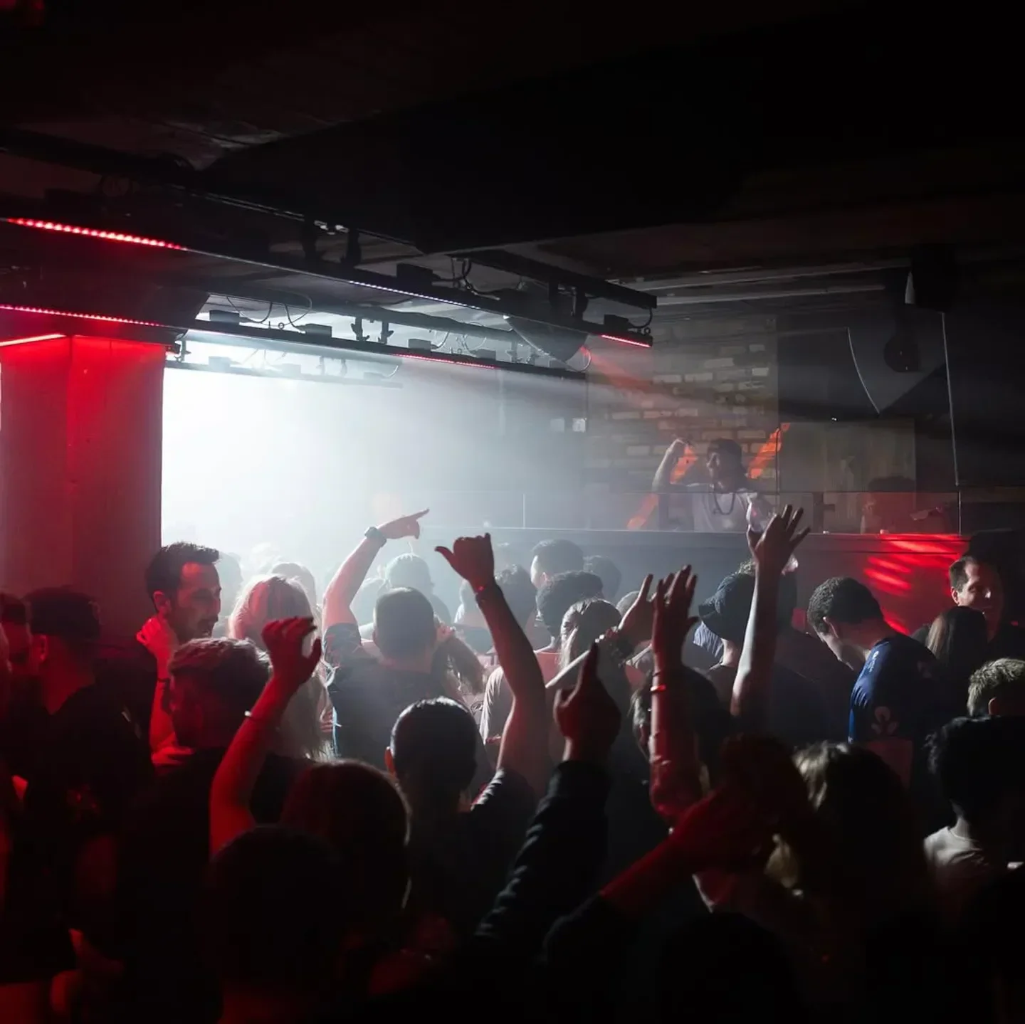 Energetic crowd dancing at Spybar nightclub in Chicago with red lighting.