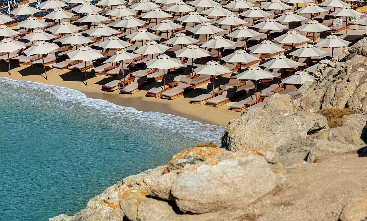 Rows of umbrellas and lounge chairs on the sandy beach at Super Paradise, Mykonos.