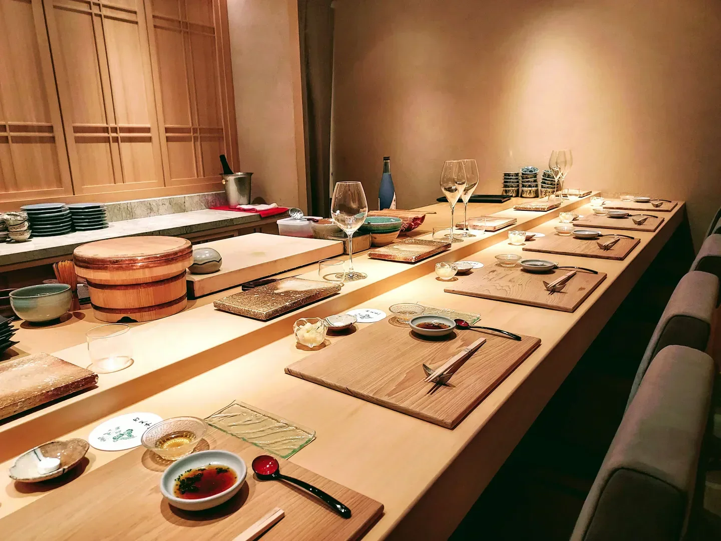 Sushi Amamoto in Taipei, elegant sushi bar setting with wood accents and detailed place settings.