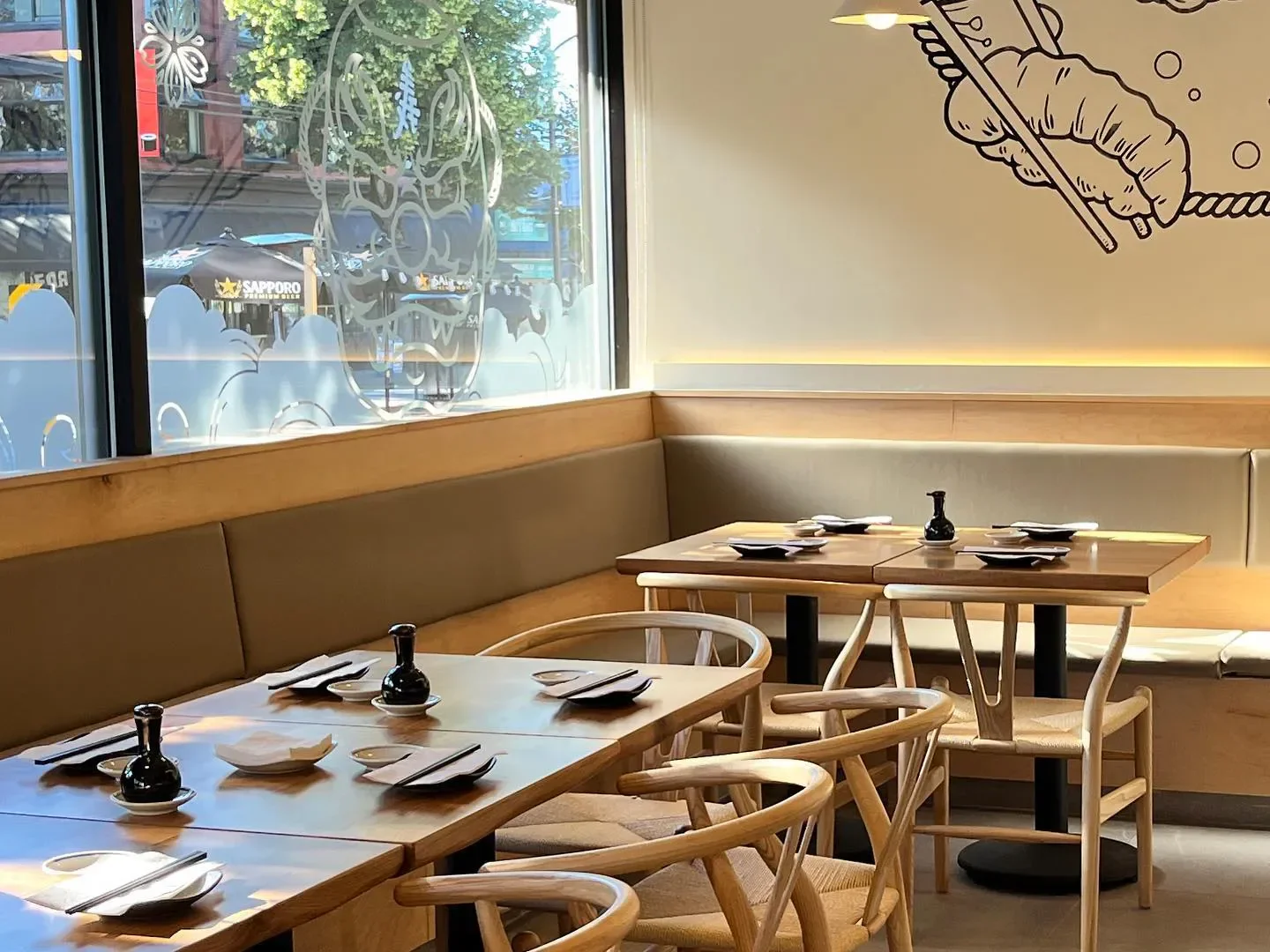 Cozy dining area inside Sushi Hil restaurant in Vancouver with wooden tables and chairs.