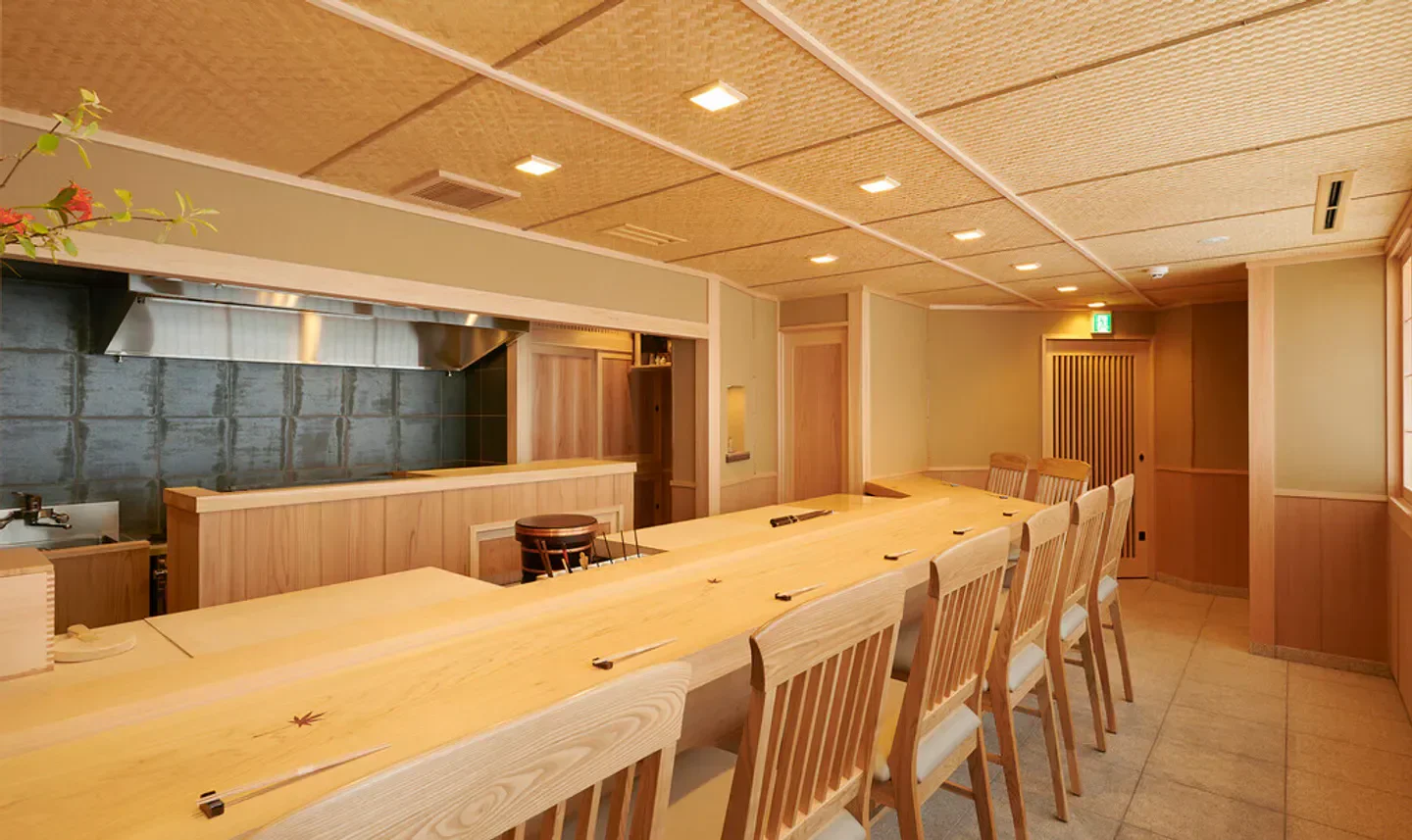 Elegant dining space at Sushi Murayama in Tokyo, featuring a long wooden counter and chairs.