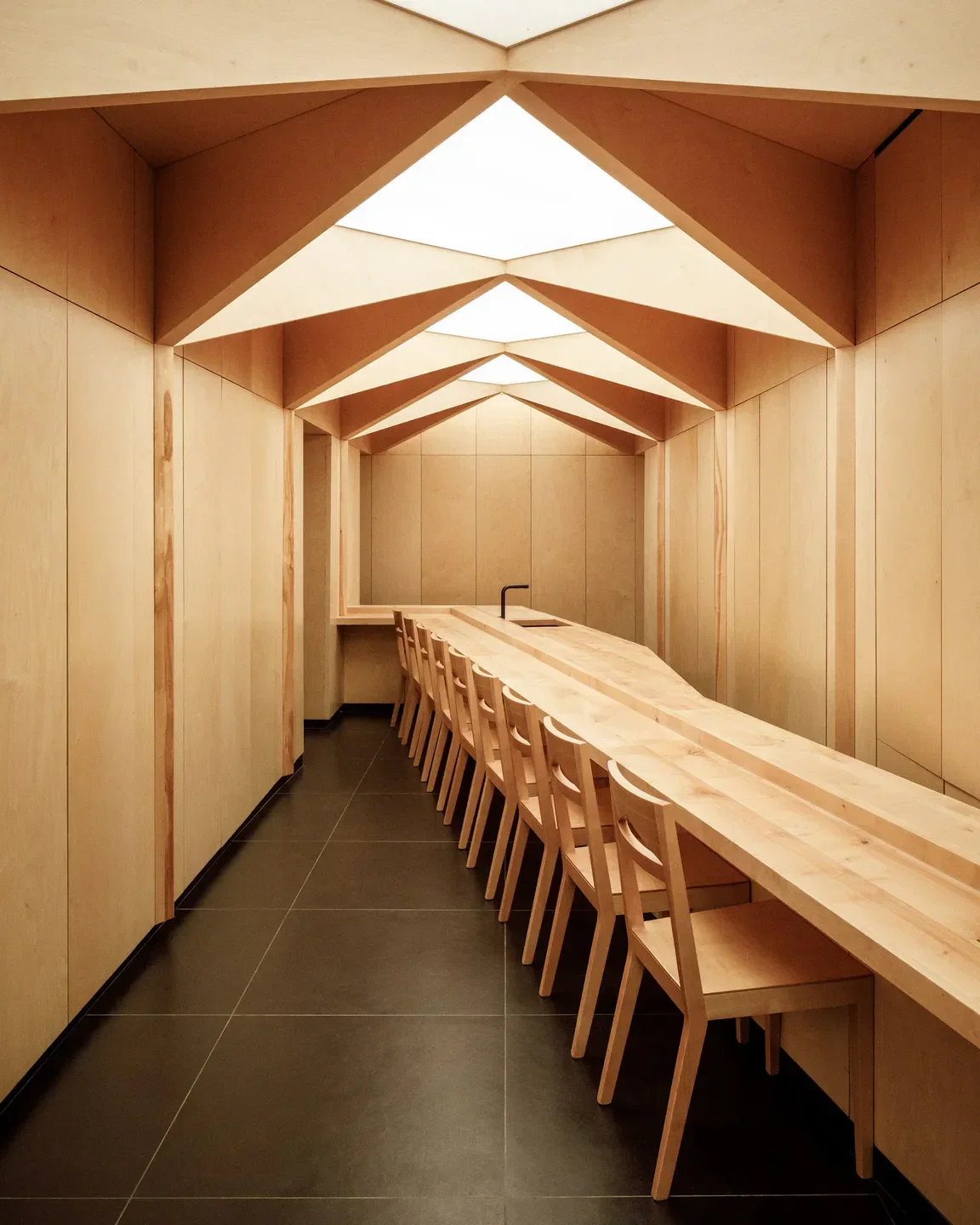 Minimalist interior at Sushi Shunei restaurant in Paris, featuring geometric wooden design.