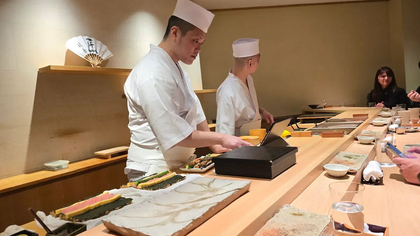 Chefs at work inside Takumi Shingo, a restaurant in Tokyo, preparing sushi for diners.