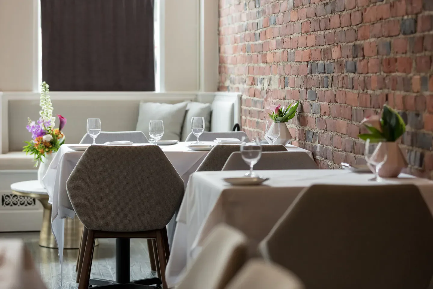 Cozy dining area at Talulla restaurant in Boston, featuring brick wall and elegant tables
