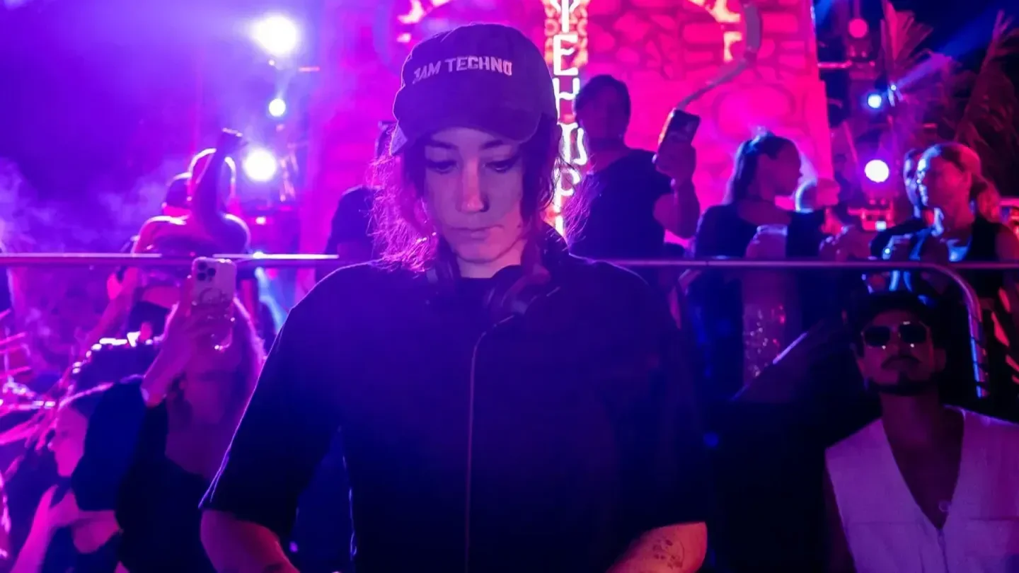 DJ at TEHMPLO nightclub in Tulum, playing music for a lively crowd under purple lights.