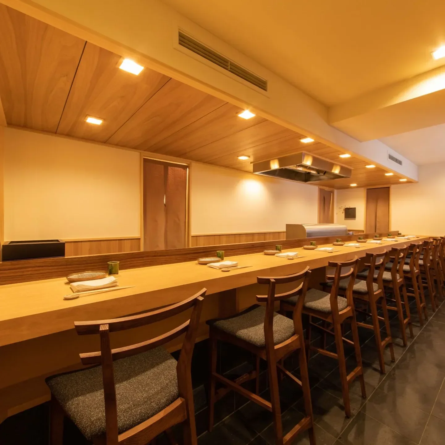 Interior of Tempura Maehira restaurant in Tokyo, showcasing elegant wood design and seating.