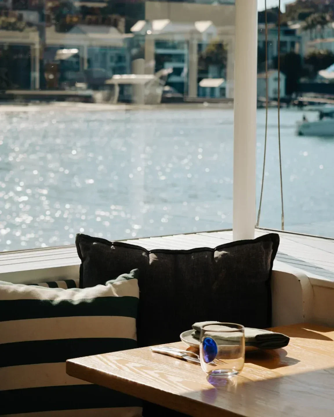 Table setting at The Boathouse Rose Bay, Sydney, with water views and stylish pillows.