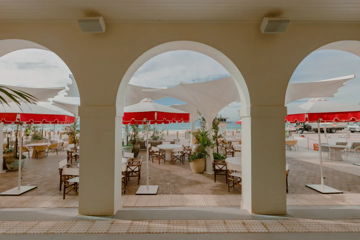 Outdoor dining at The Dining Room at Promenade in Sydney, featuring red and white umbrellas