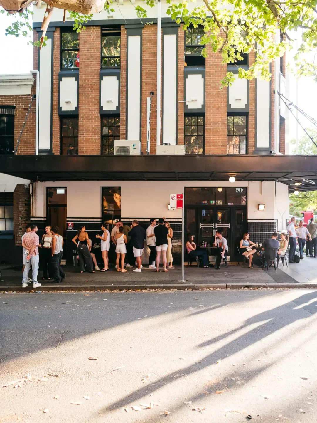 People gathering outside The Dolphin Hotel restaurant in Sydney, enjoying drinks and conversation.