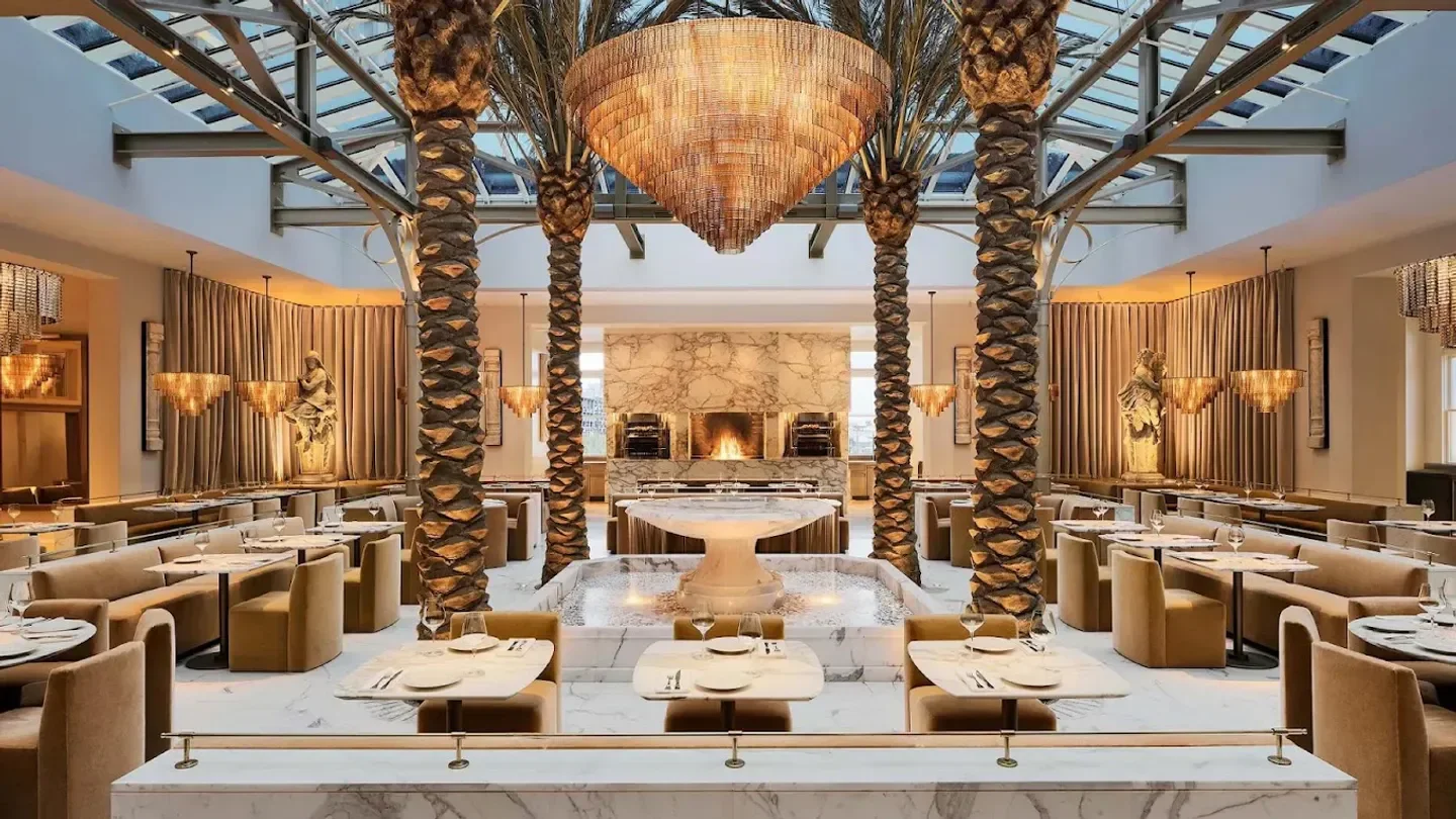 Elegant interior of The Palm Court at RH San Francisco, with palm trees and a water feature.