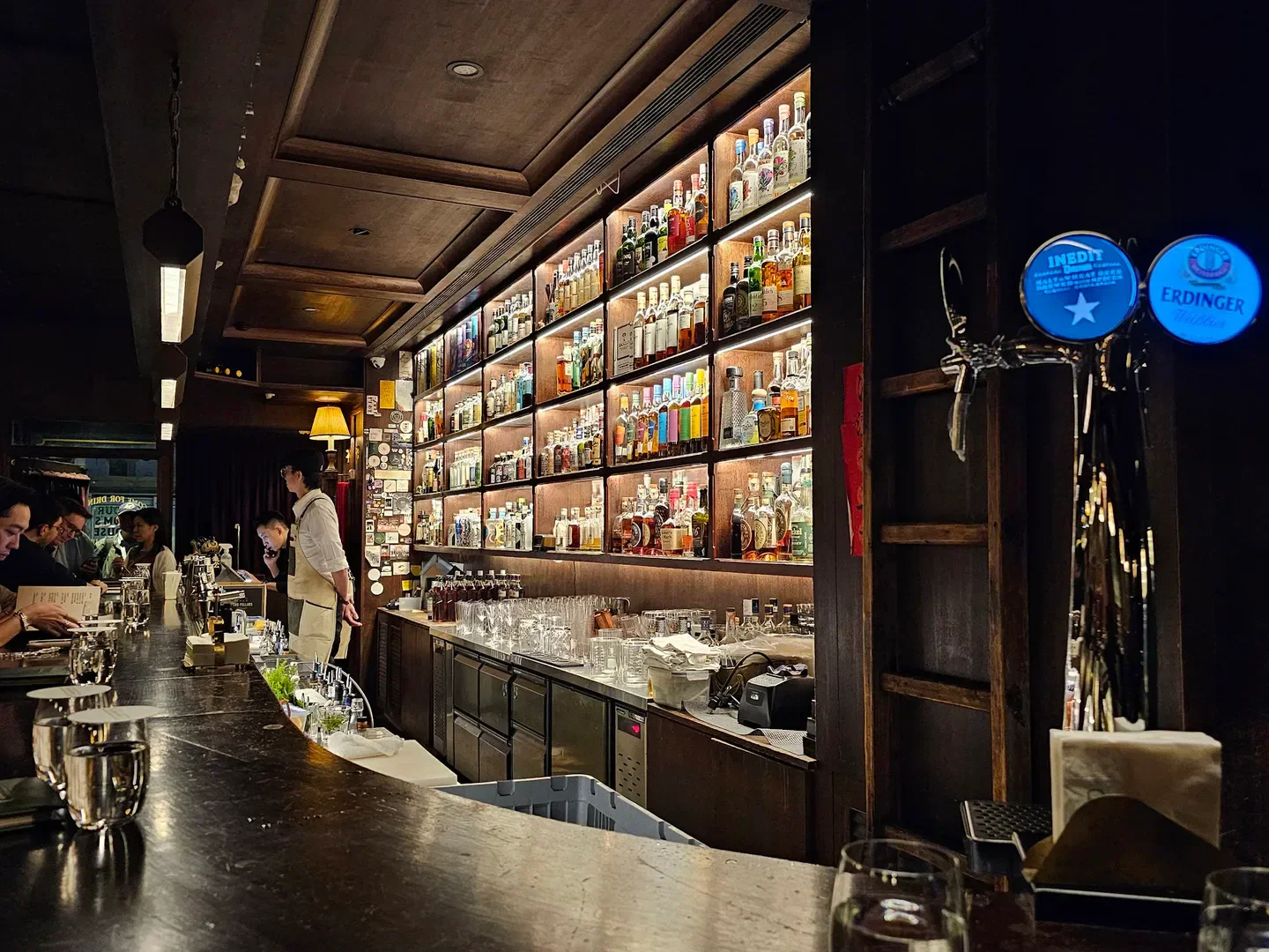 Interior bar at The Public House in Taipei, featuring a backlit liquor display and patrons.
