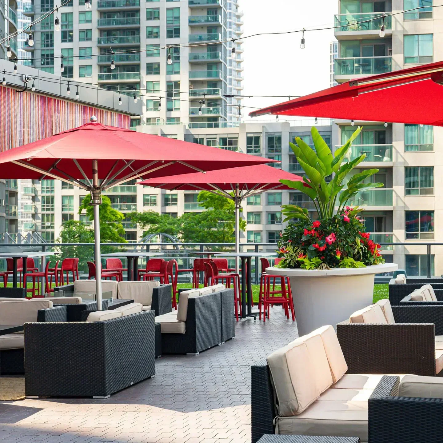 Outdoor seating at The Roof at SOCO in Toronto with red umbrellas and city views.