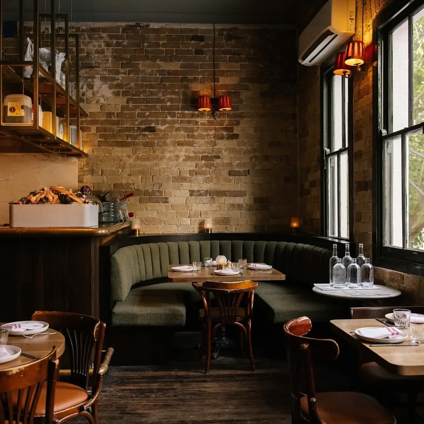 Cozy dining area at The Rover restaurant in Sydney, featuring a green booth and wooden tables.