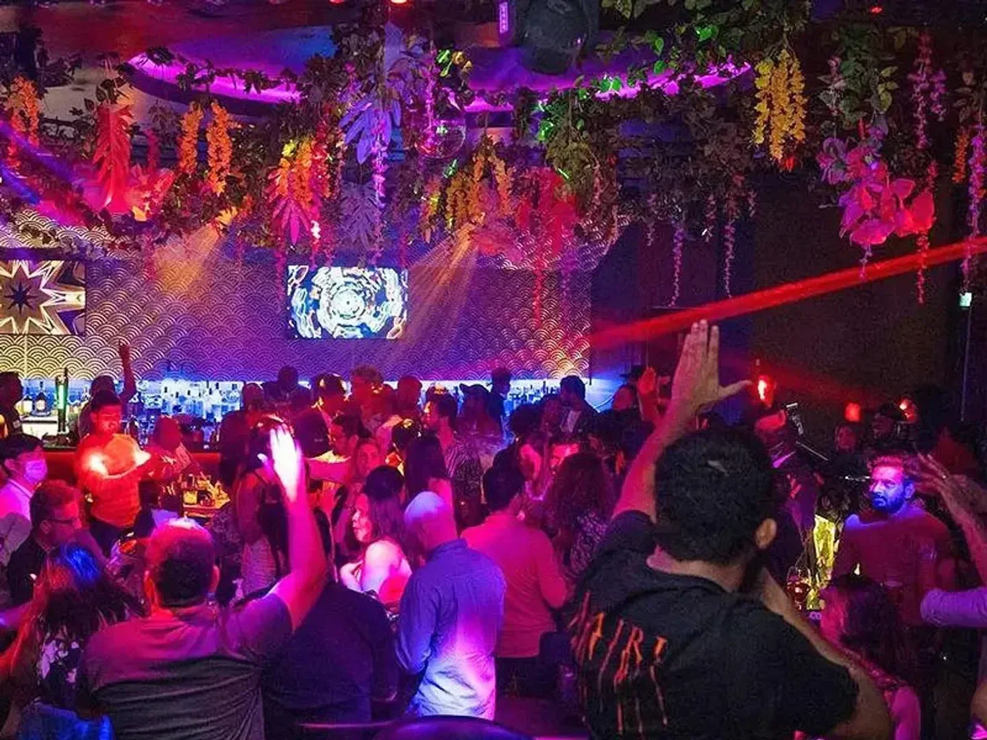 Energetic crowd partying inside The Vogue Club in Doha, Qatar, with vibrant lighting and decor.