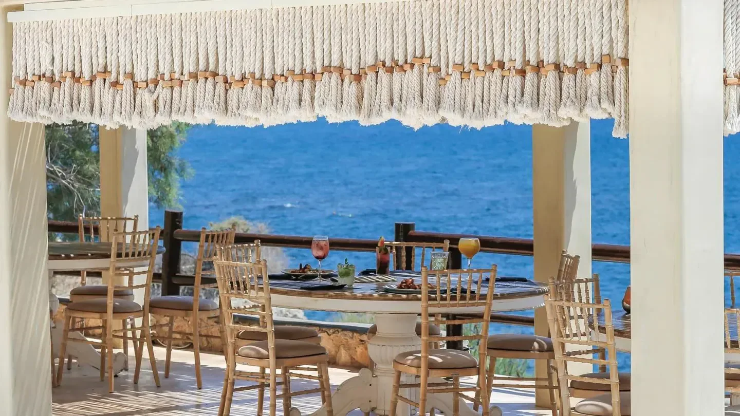 Dining scene at Theros Wave Bar in Santorini with ocean view and stylish decor.