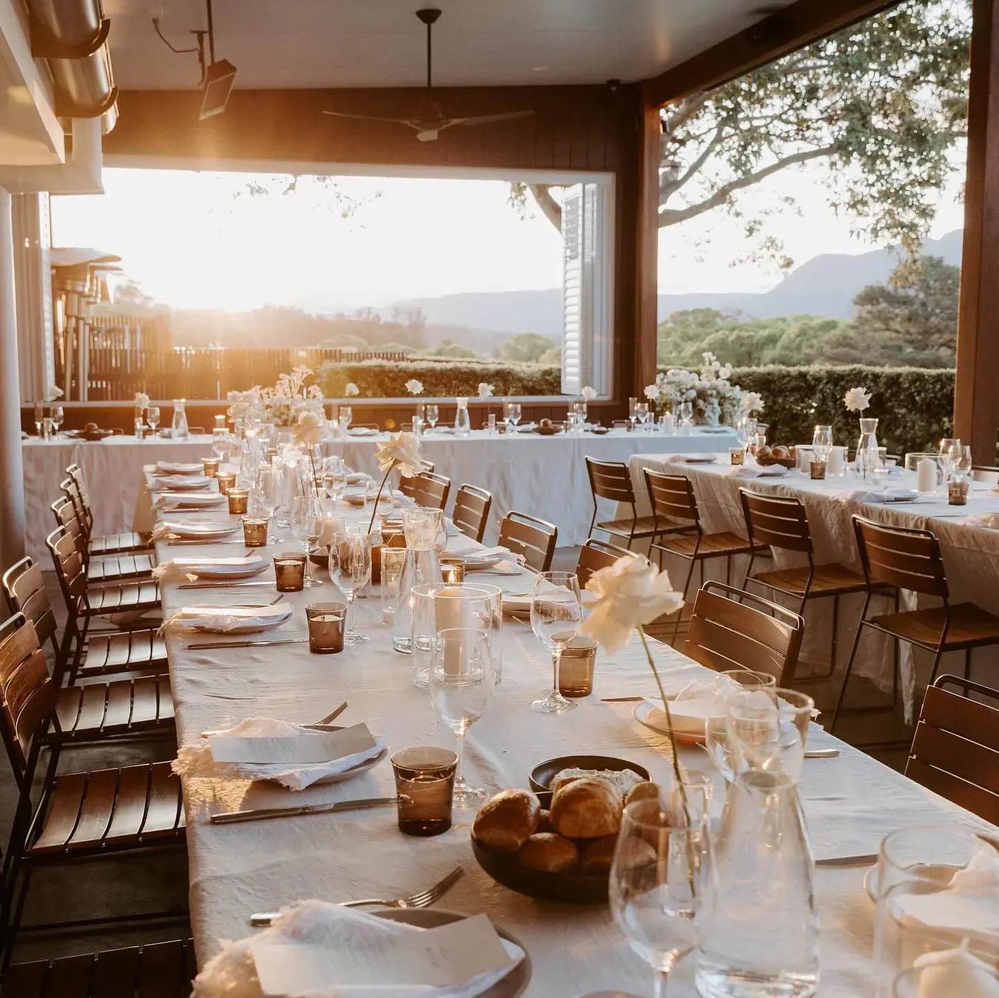 Outdoor dining setup at Three Blue Ducks restaurant in Sydney with sunset views.