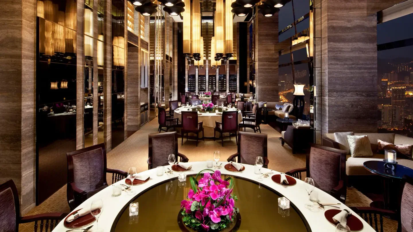 Elegant dining room at Tin Lung Heen in Hong Kong, featuring city skyline views at night