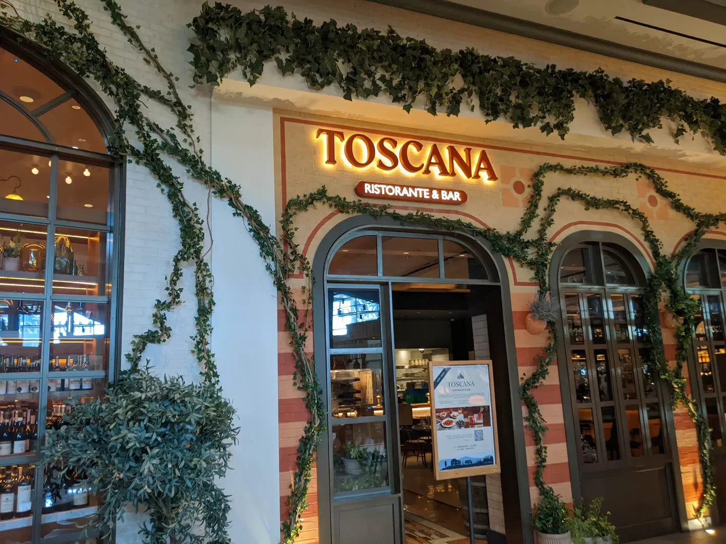 Entrance of Toscana Ristorante & Bar in Las Vegas with ivy covered walls and arched windows.