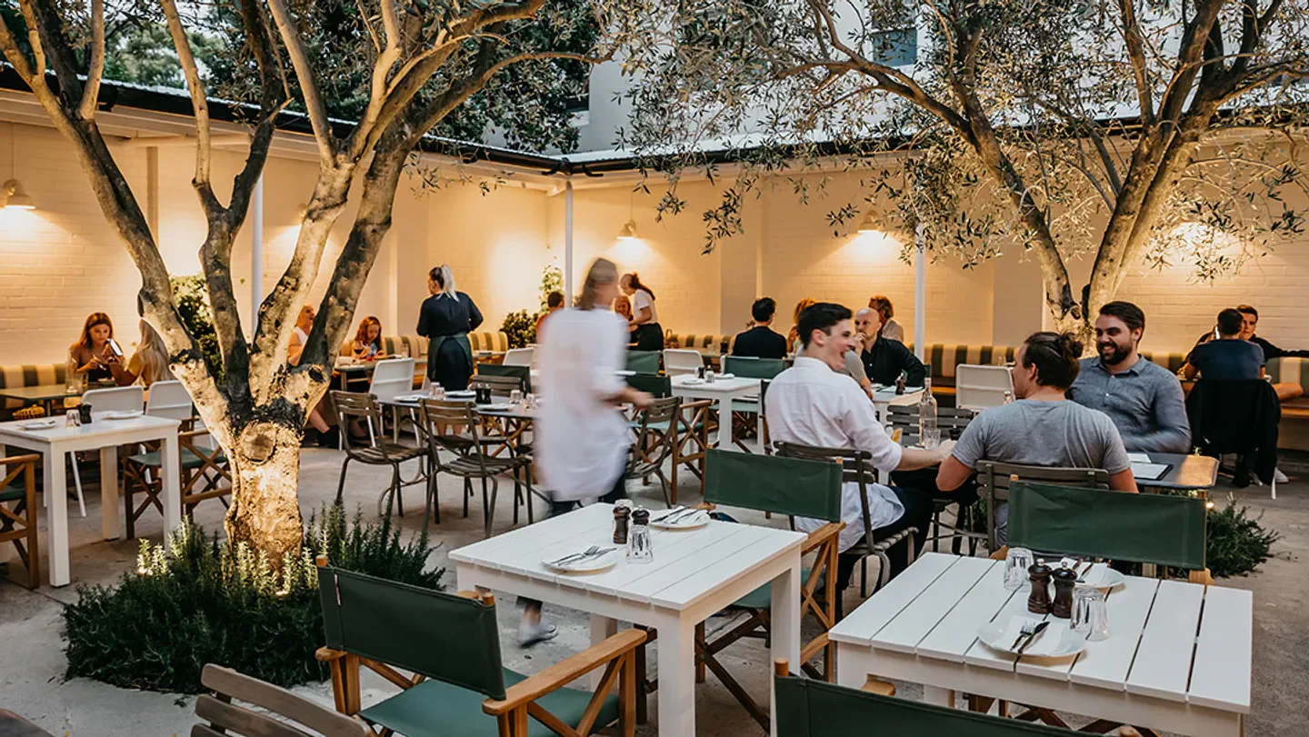 Outdoor dining at Totti’s Bondi restaurant in Sydney, featuring tree and tables.