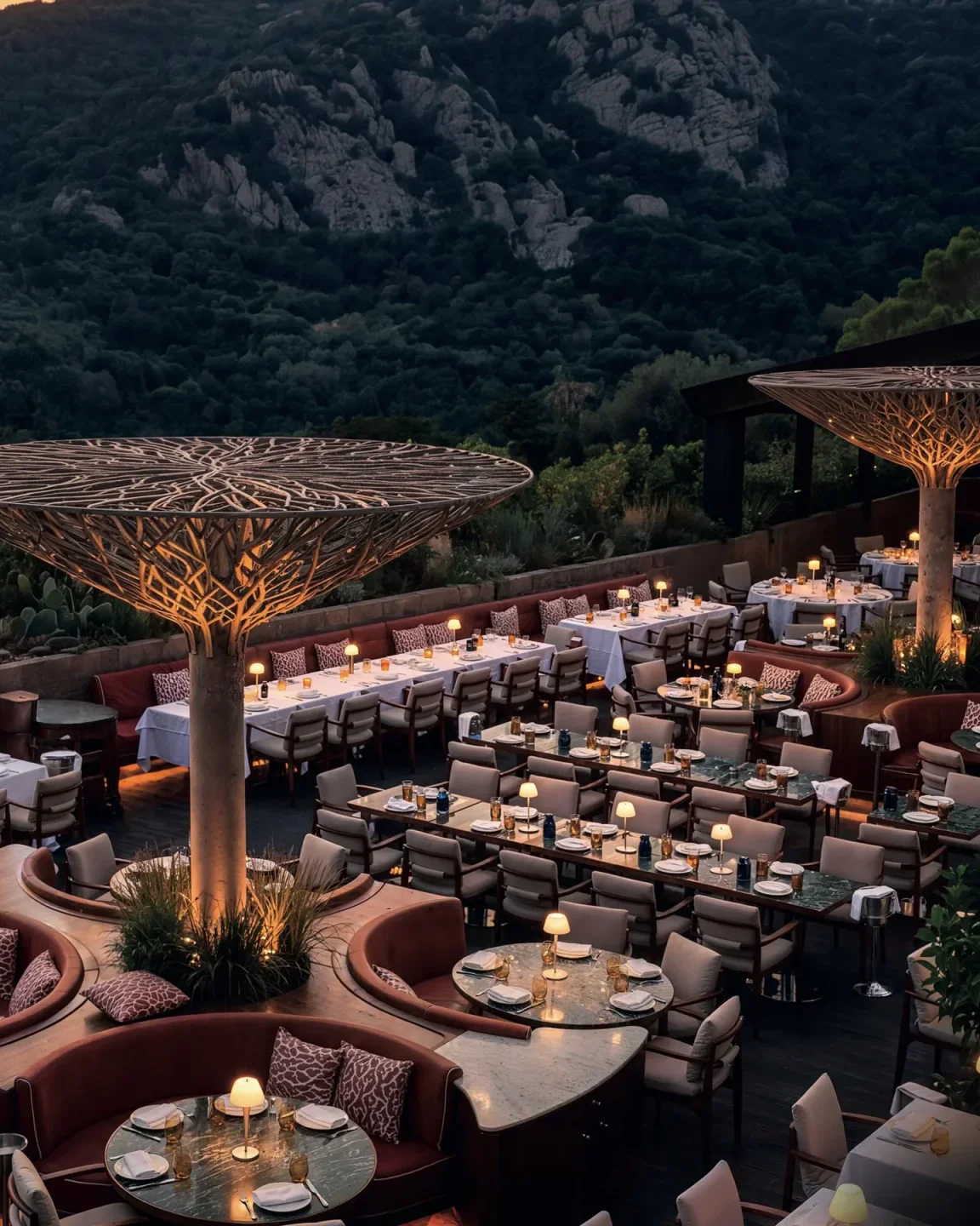 Twiga Porto Cervo elegant outdoor dining area with tree-like canopies and mountain backdrop