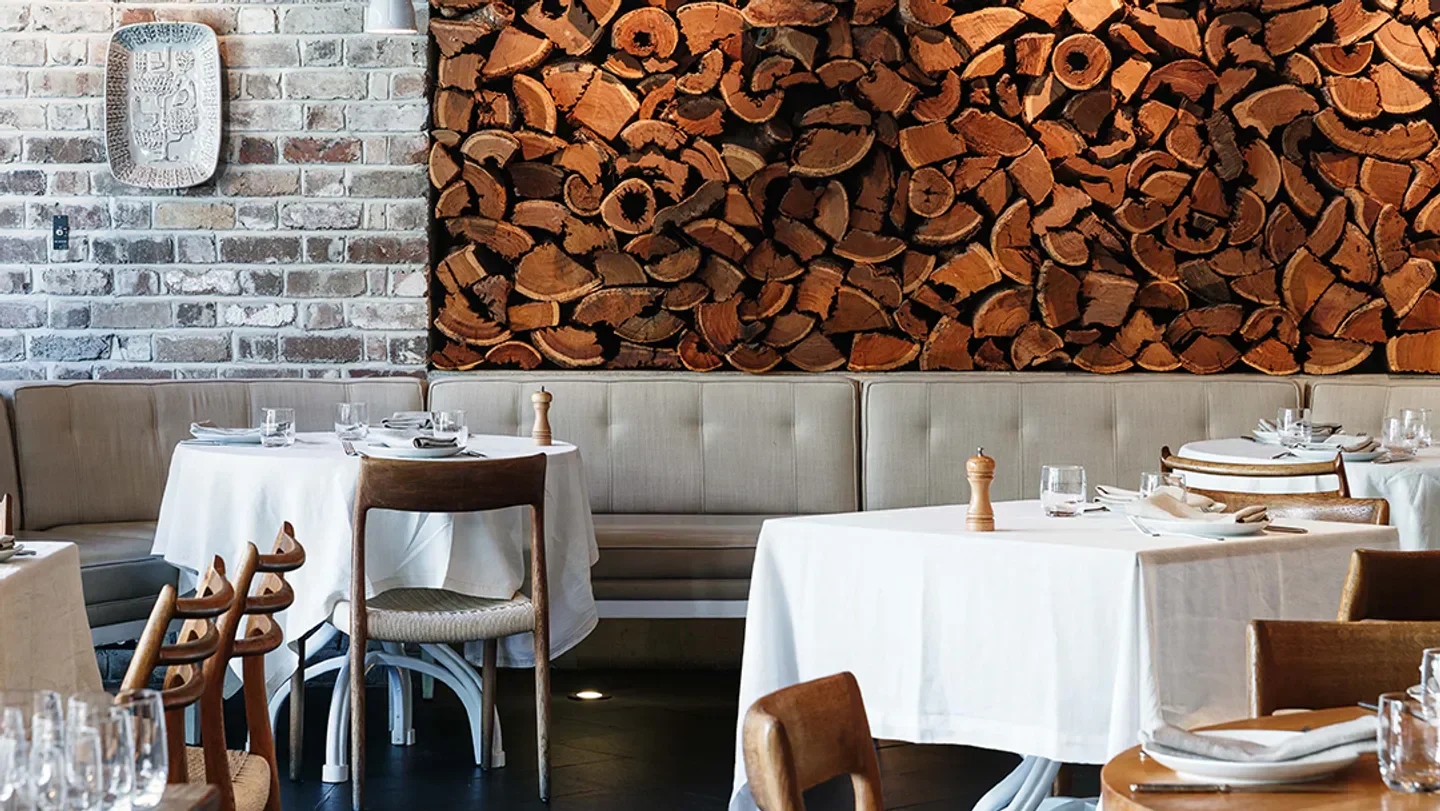 Stylish interior dining room at Uccello in Sydney featuring wood-paneled wall and table settings