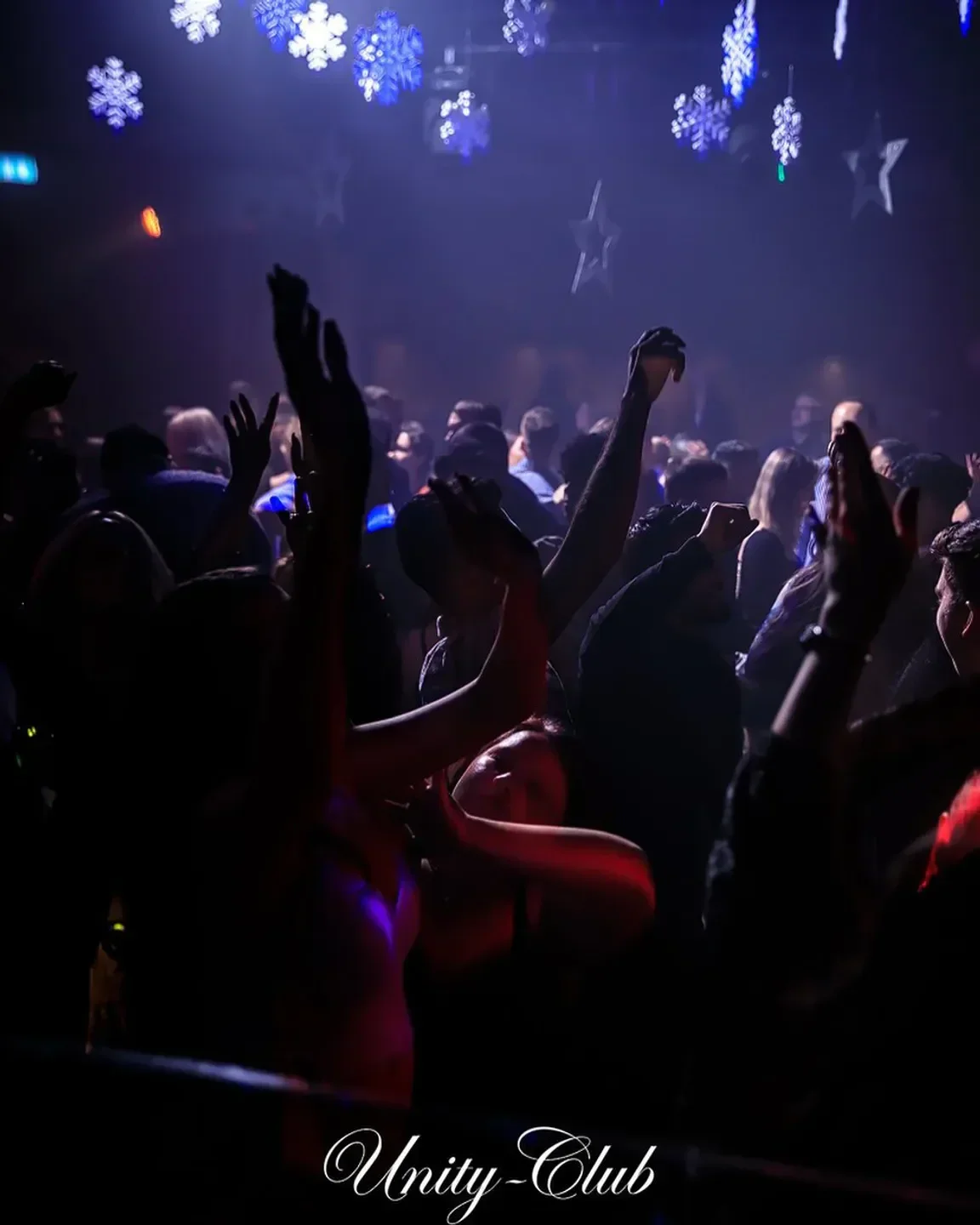 Energetic crowd dancing at Unity Club in Montreal with festive decorations.