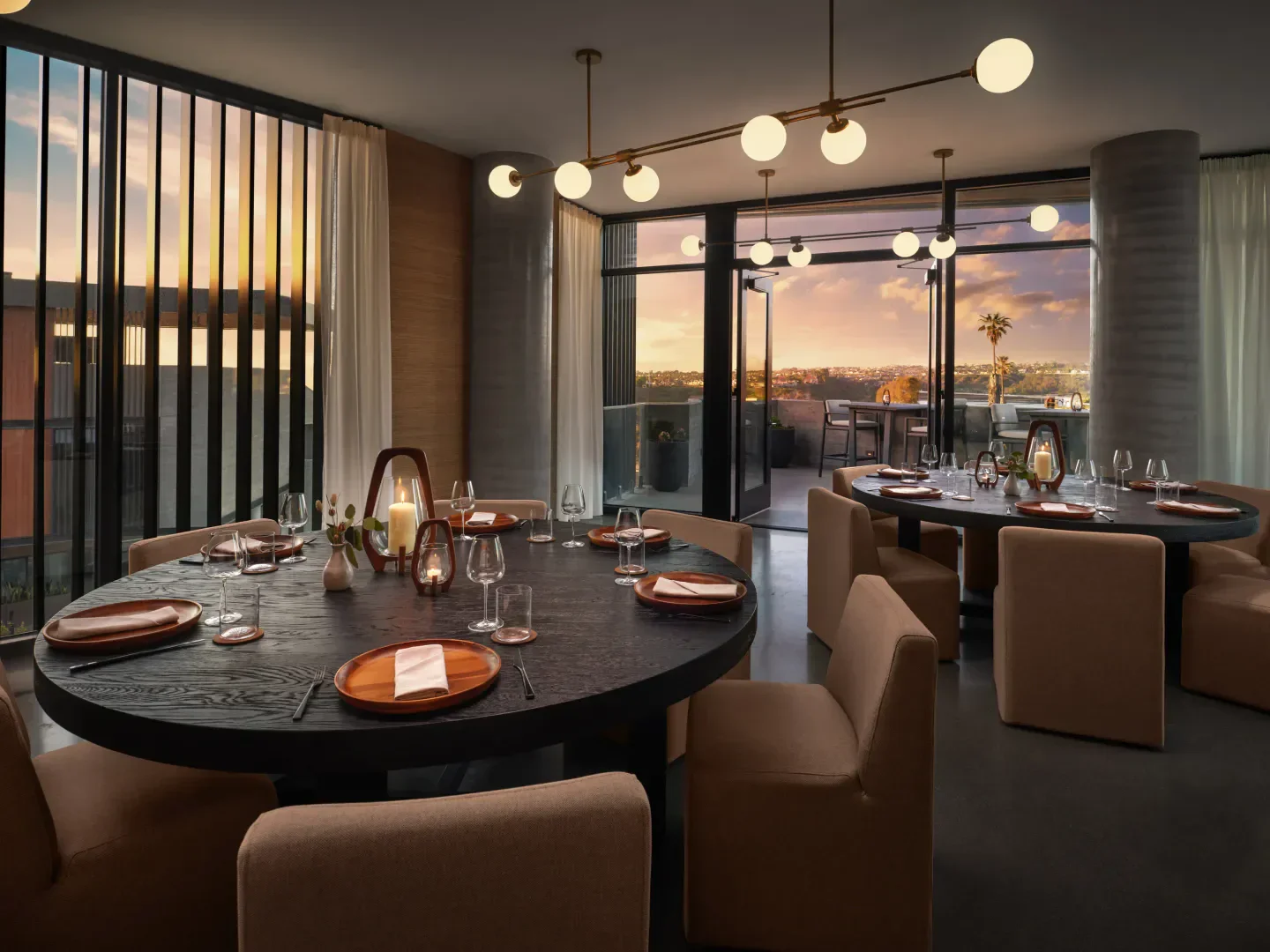 Elegant dining room at VAGA San Diego with sunset views and a well-set table.