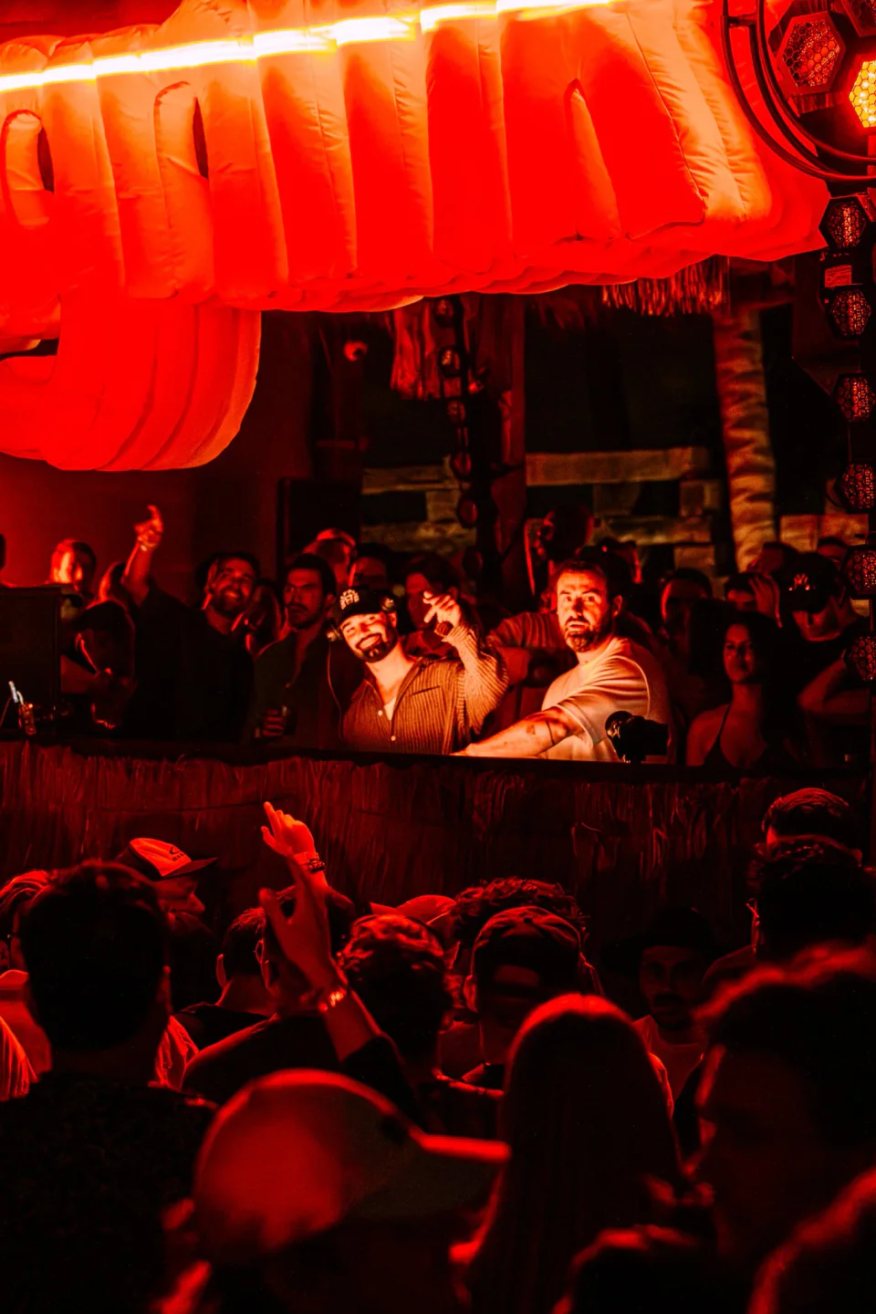 Energetic crowd at Vagalume nightclub in Tulum, Mexico enjoying the party atmosphere with DJs and red lighting.