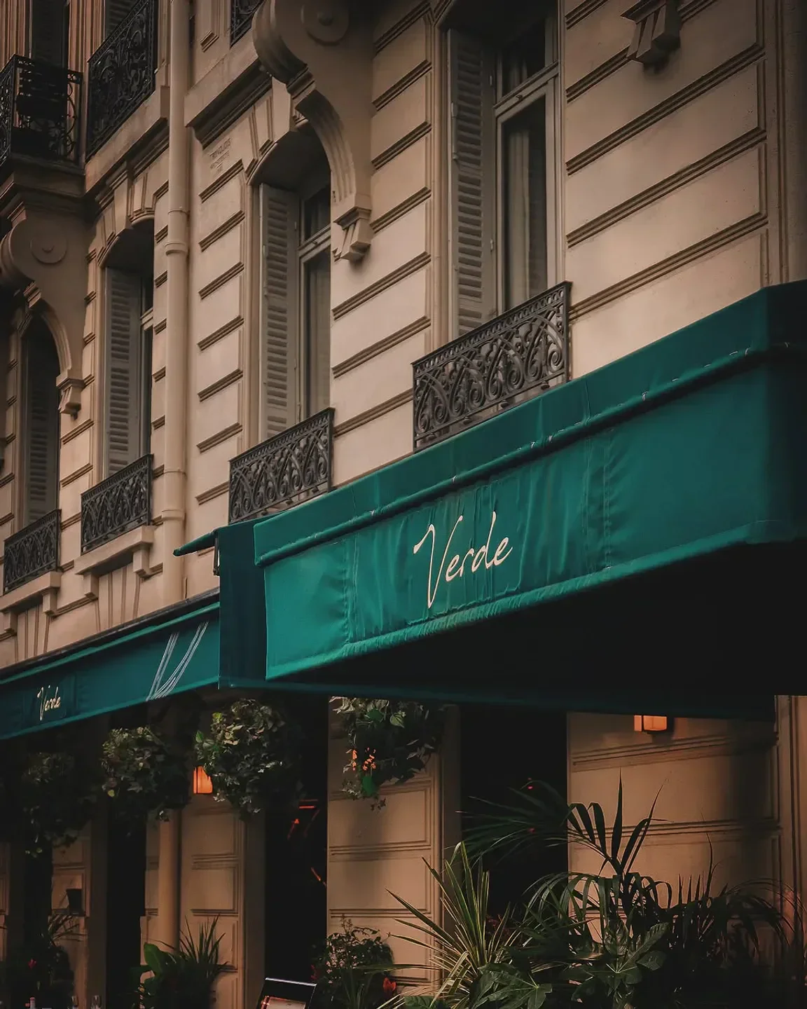 Exterior view of Verde restaurant in Paris with green awning and elegant architecture.