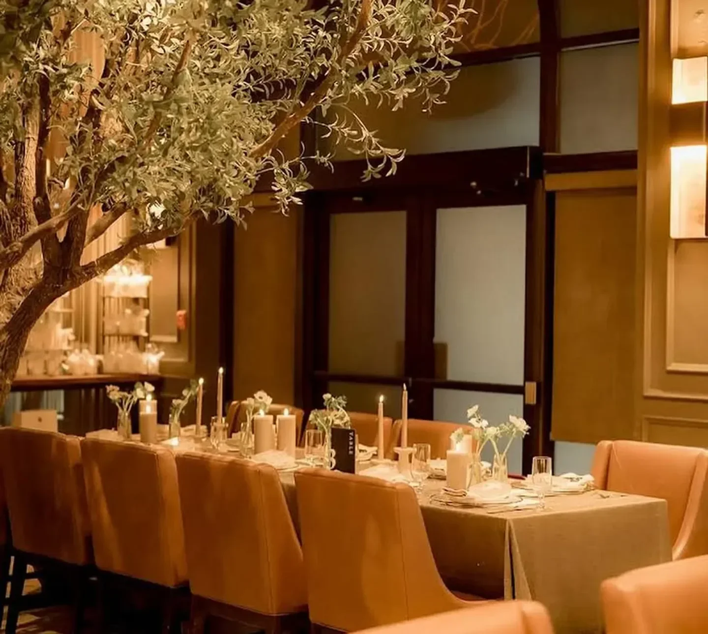 Cozy dining room at Via Allegro Ristorante in Toronto, featuring candlelit tables and a tree.