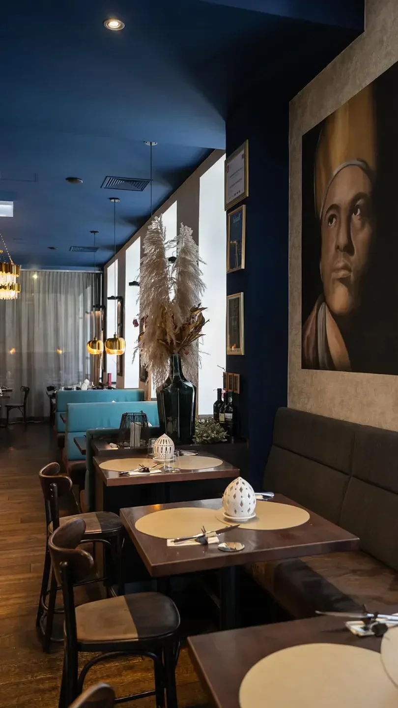 Interior of Via Toledo Enopizzeria in Vienna, featuring tables and a large painting.