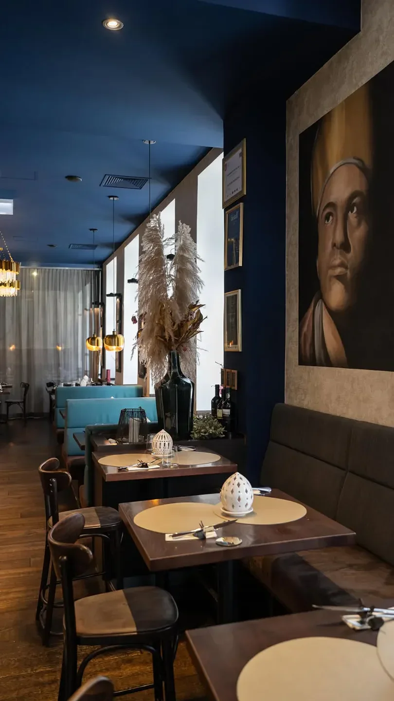 Interior of Via Toledo Enopizzeria in Vienna, featuring tables and a large painting.