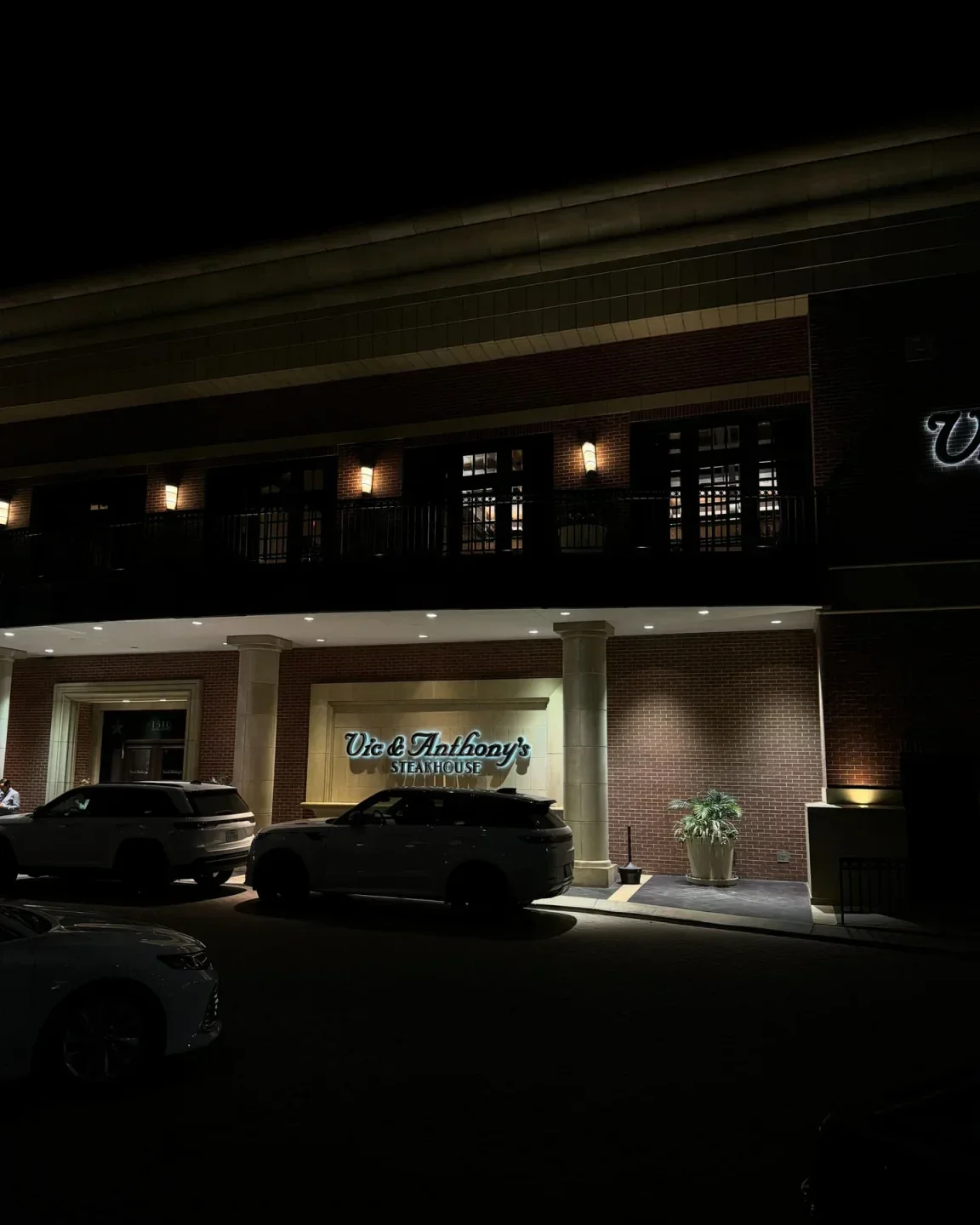 Exterior of Vic & Anthony's Steakhouse in Las Vegas at night with cars parked outside