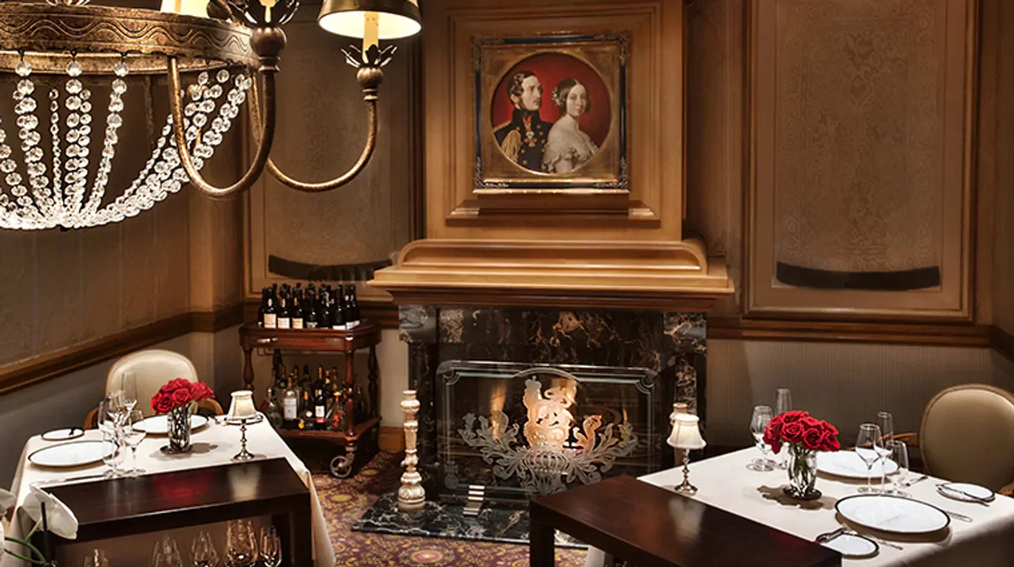 Cozy dining room at Victoria & Albert's in Orlando with fireplace, tables, and chandelier.