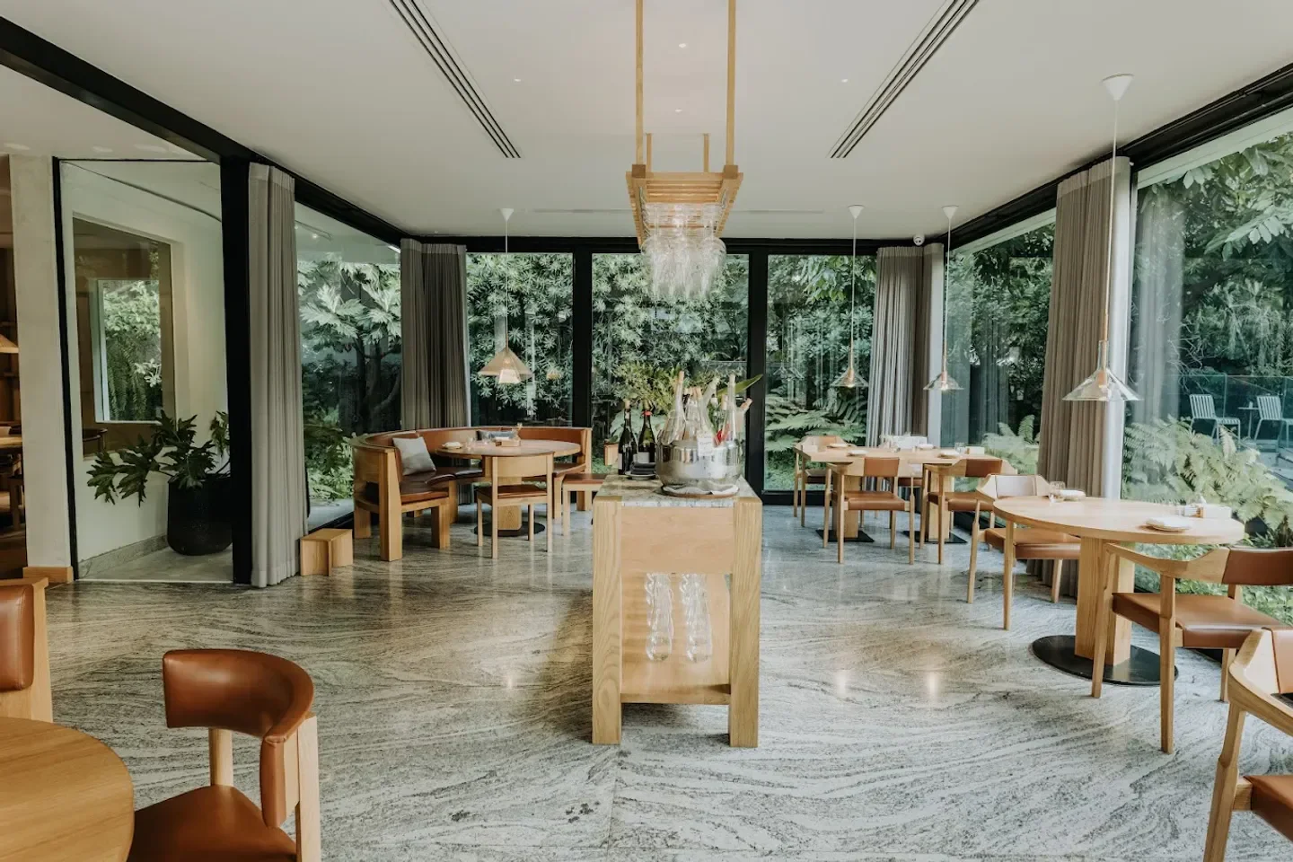 Elegant dining room at Villa Frantzén in Bangkok, with views of lush greenery.