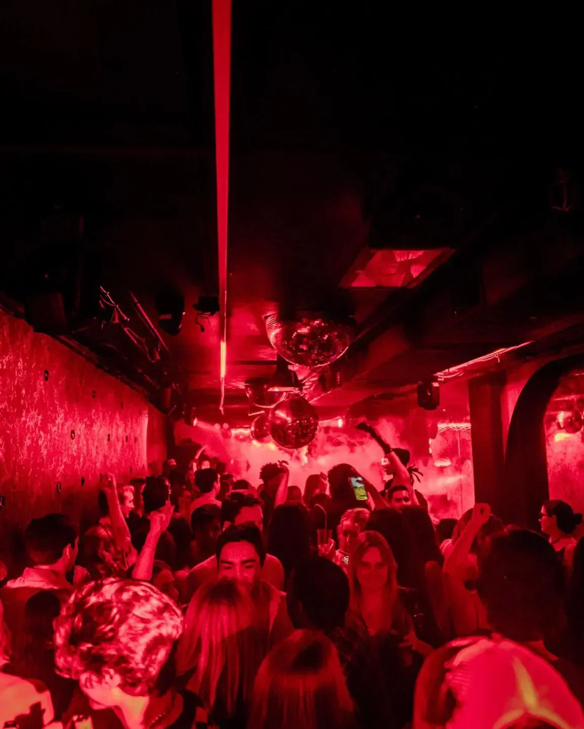 Inside Virgo nightclub in New York City, a crowded dance floor with red lighting and disco balls.