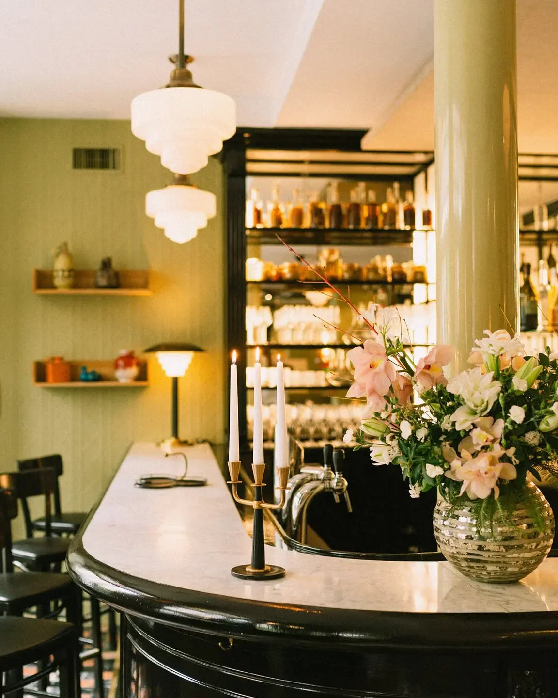 Elegant bar interior at Virtus restaurant in Paris, featuring candles and floral arrangement.