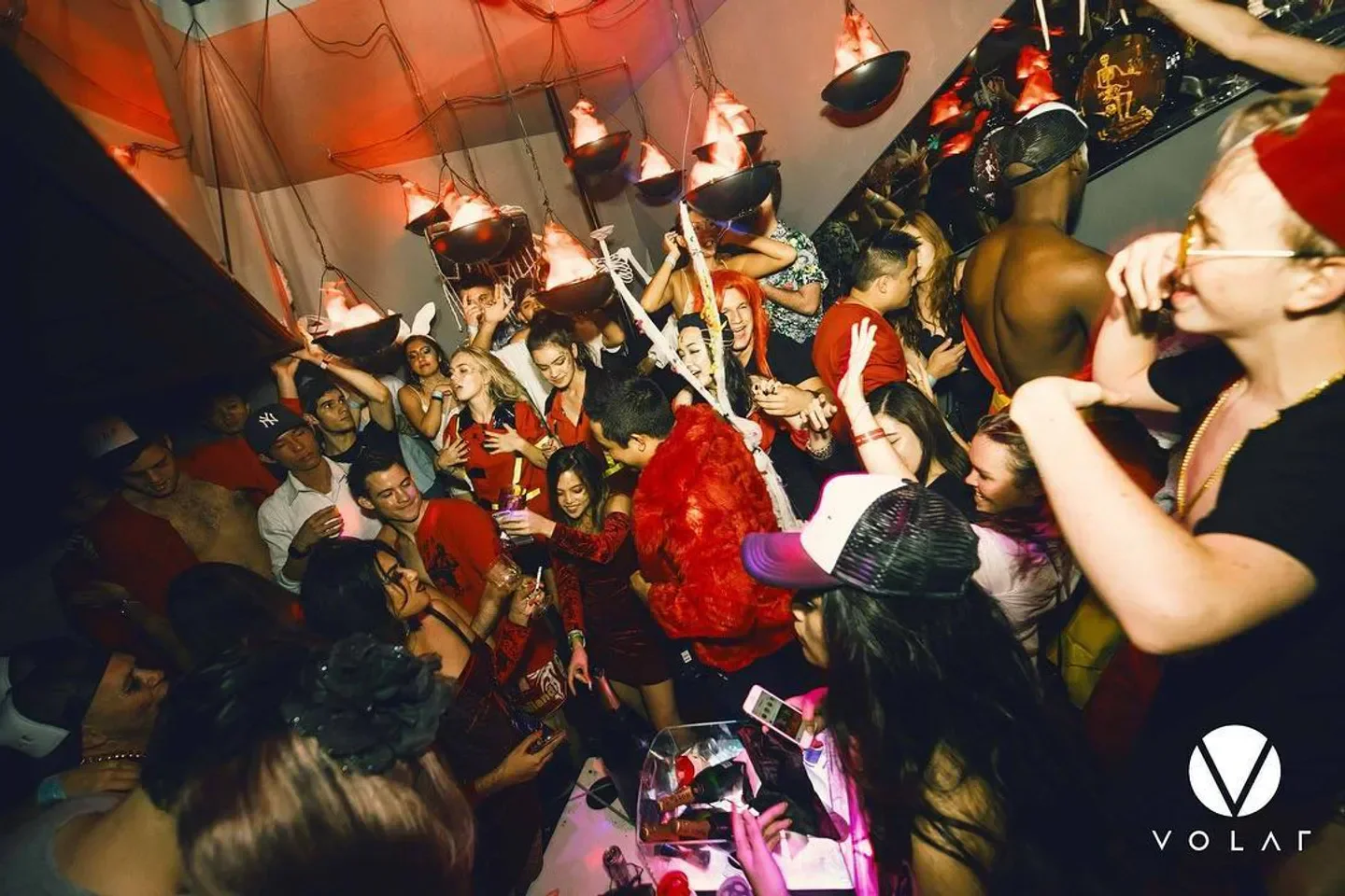 Energetic crowd partying inside Volar nightclub in Hong Kong with party lights and music.