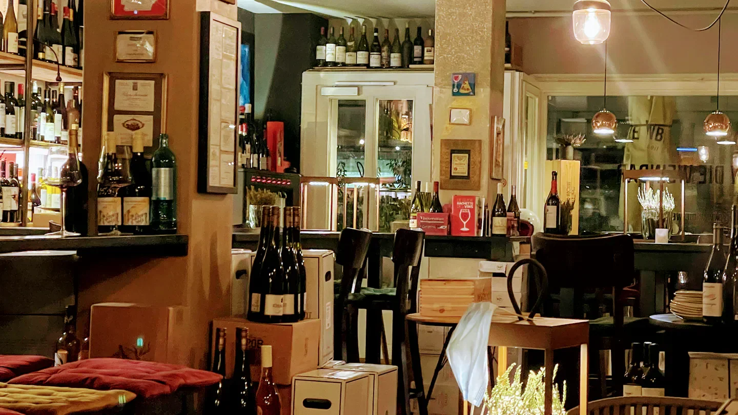 Cozy interior of W die Weinbar in Hamburg, showcasing bottles of wine and a stylish bar.