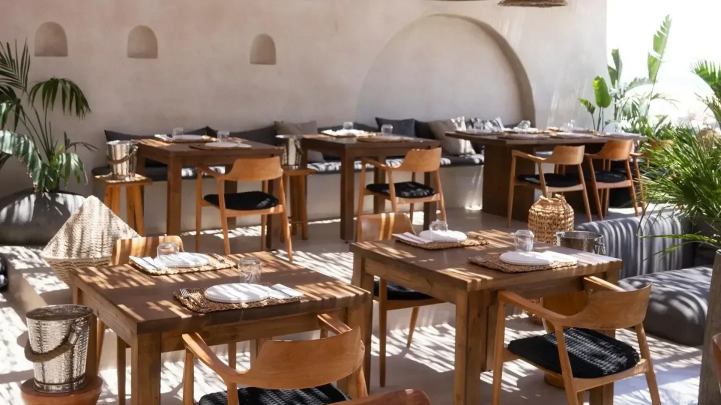 Outdoor seating at Wet Stories beach club in Santorini, wooden tables and chairs.