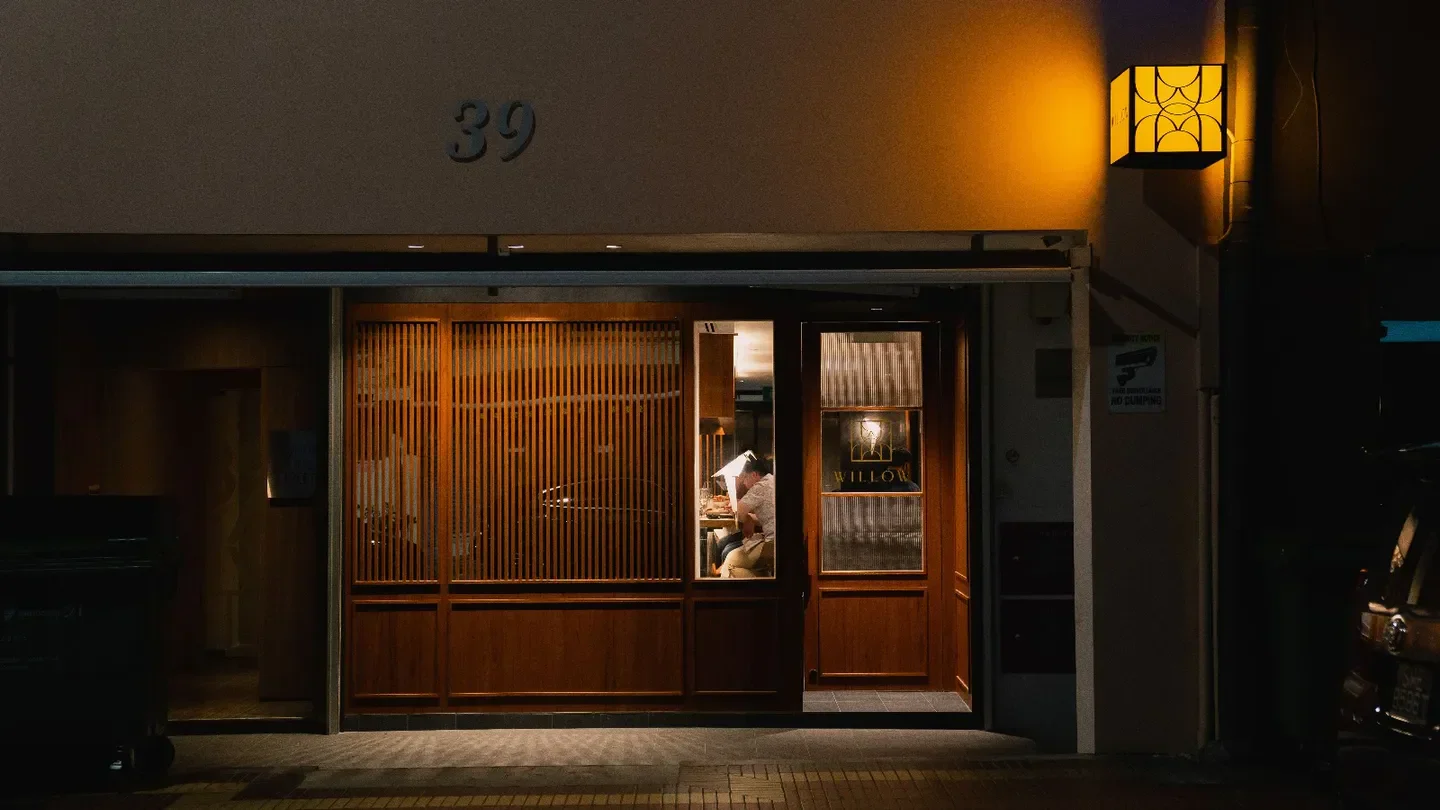 Entrance to Willow restaurant in Singapore at night with wooden facade and warm lighting.