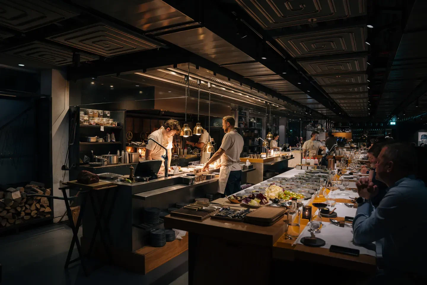 Chefs preparing food at Wils in Amsterdam, with diners enjoying the meal.