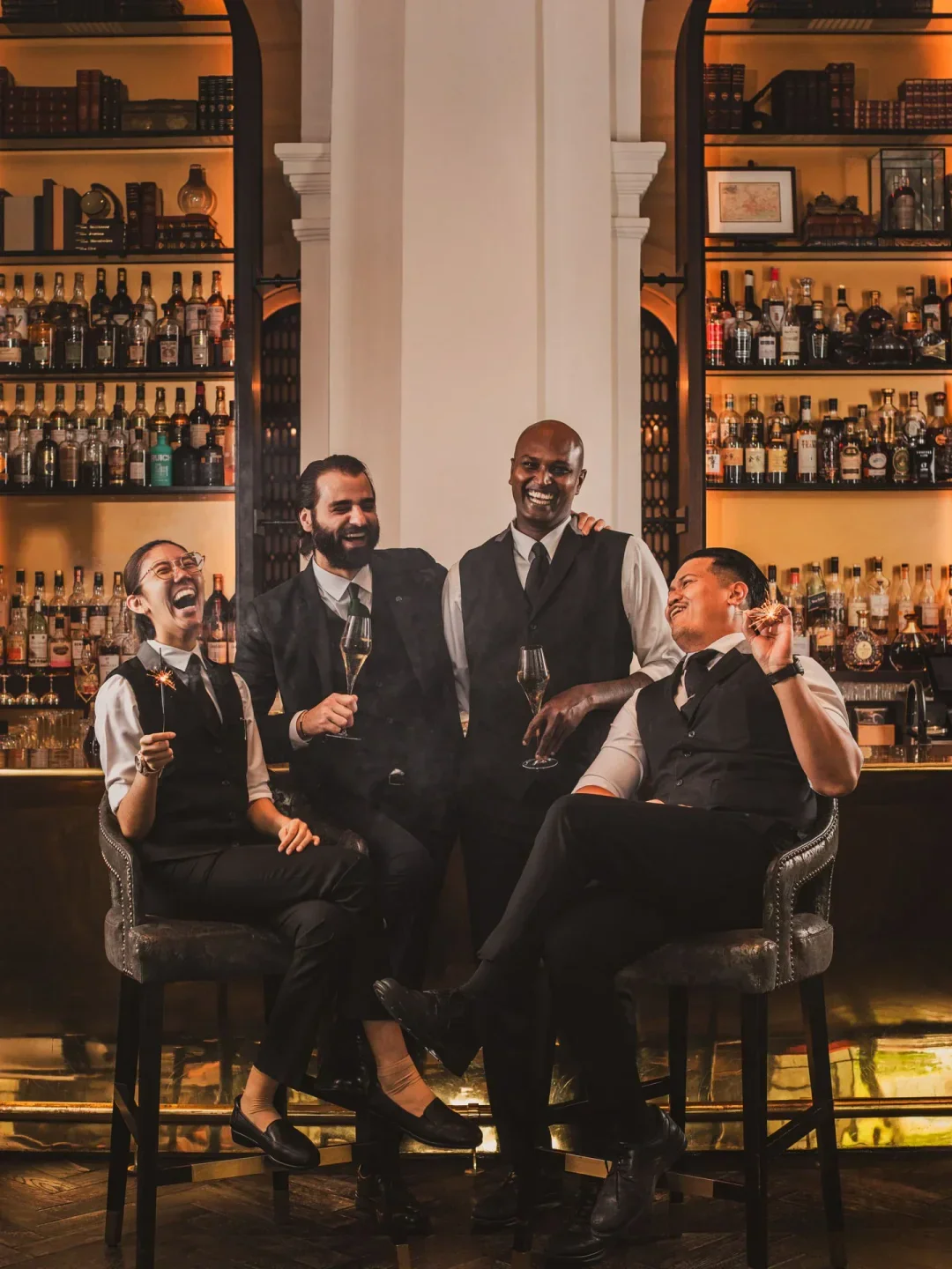 Group of happy staff at the Writers Bar in Singapore, posing at the bar