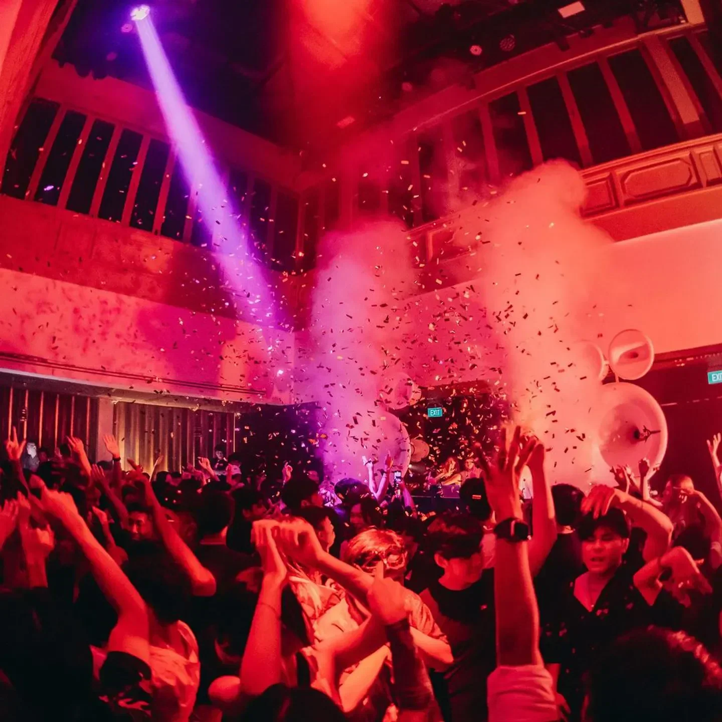Energetic crowd partying at Yang Club in Singapore with confetti and vibrant lighting.