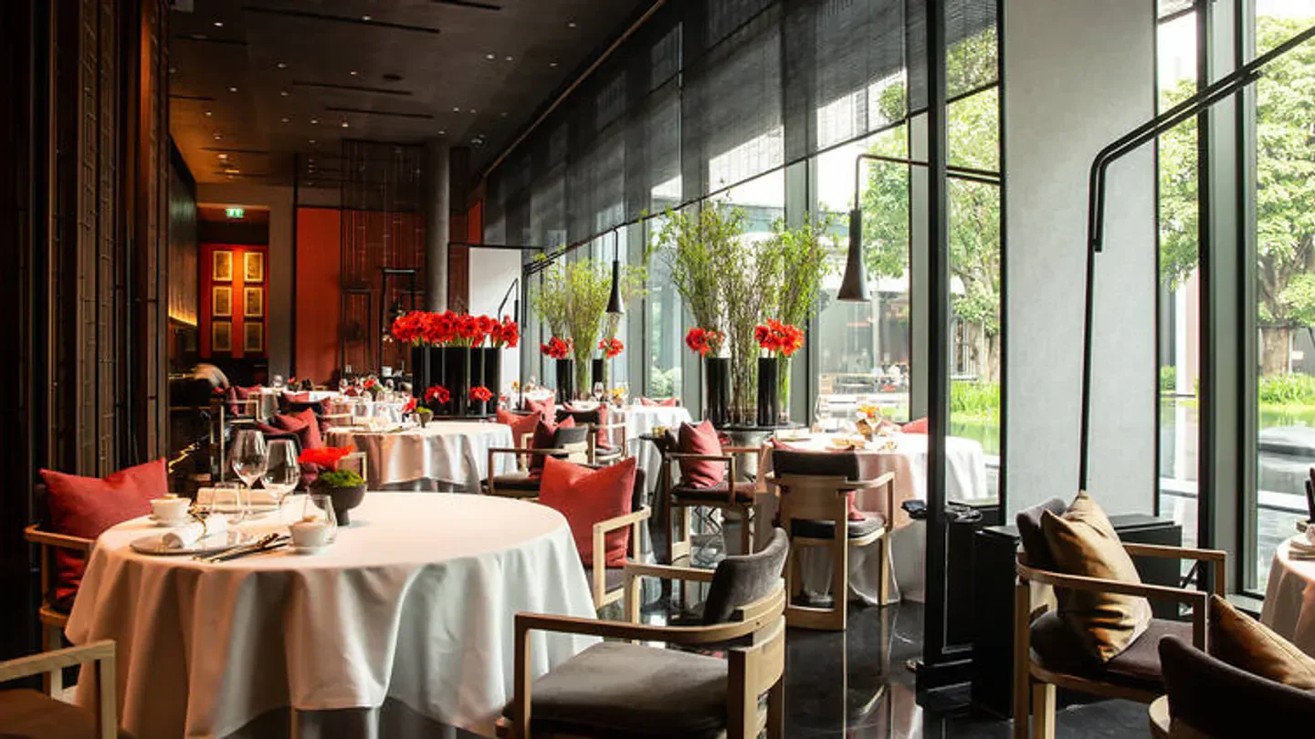 Elegant dining room at Yu Ting Yuan restaurant in Bangkok, featuring round tables and flowers