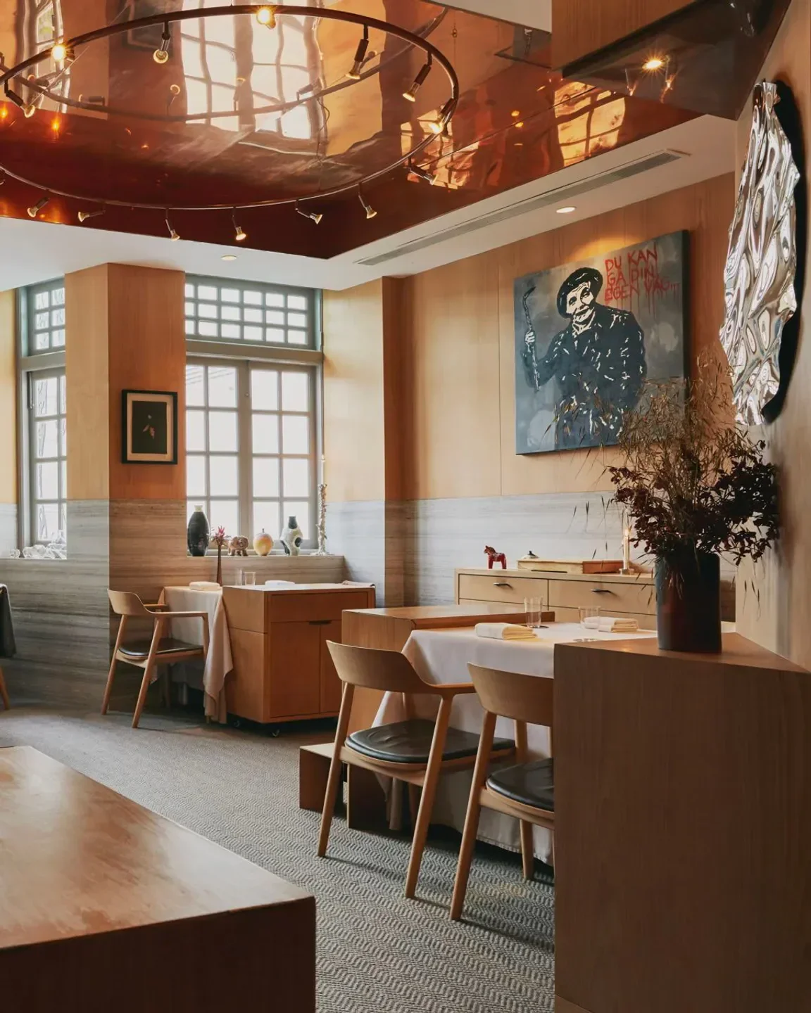 Elegant dining room interior at Zén restaurant in Singapore, featuring stylish wooden furniture and art.
